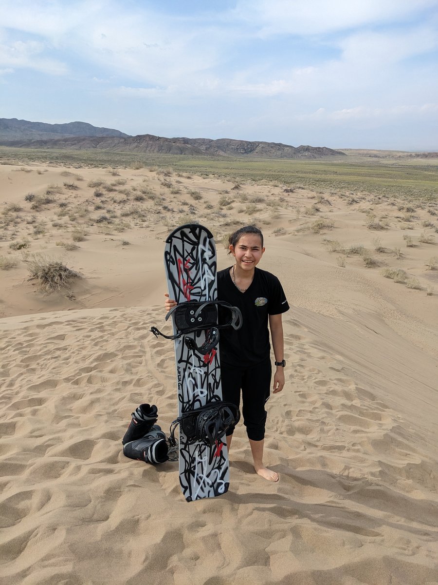 Guest holding sandboard on the Singing Dune — sandboarding at Altyn-Emel