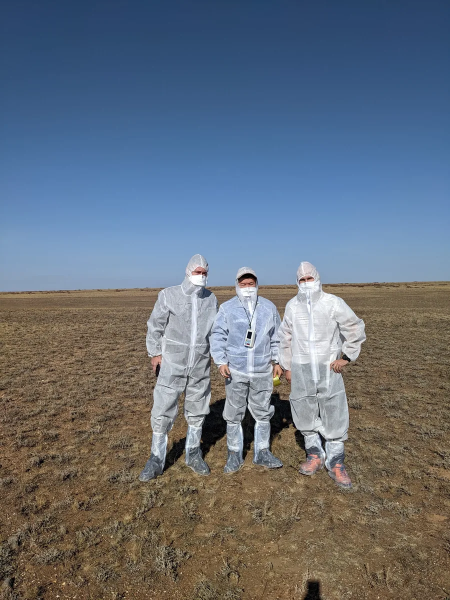 Three visitors in full protective suits on the open steppe at Semipalatinsk nuclear test site