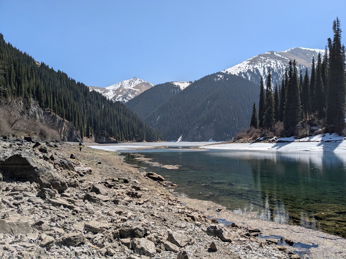 Kolsai Lake in early spring with snow-edged shoreline and emerald water