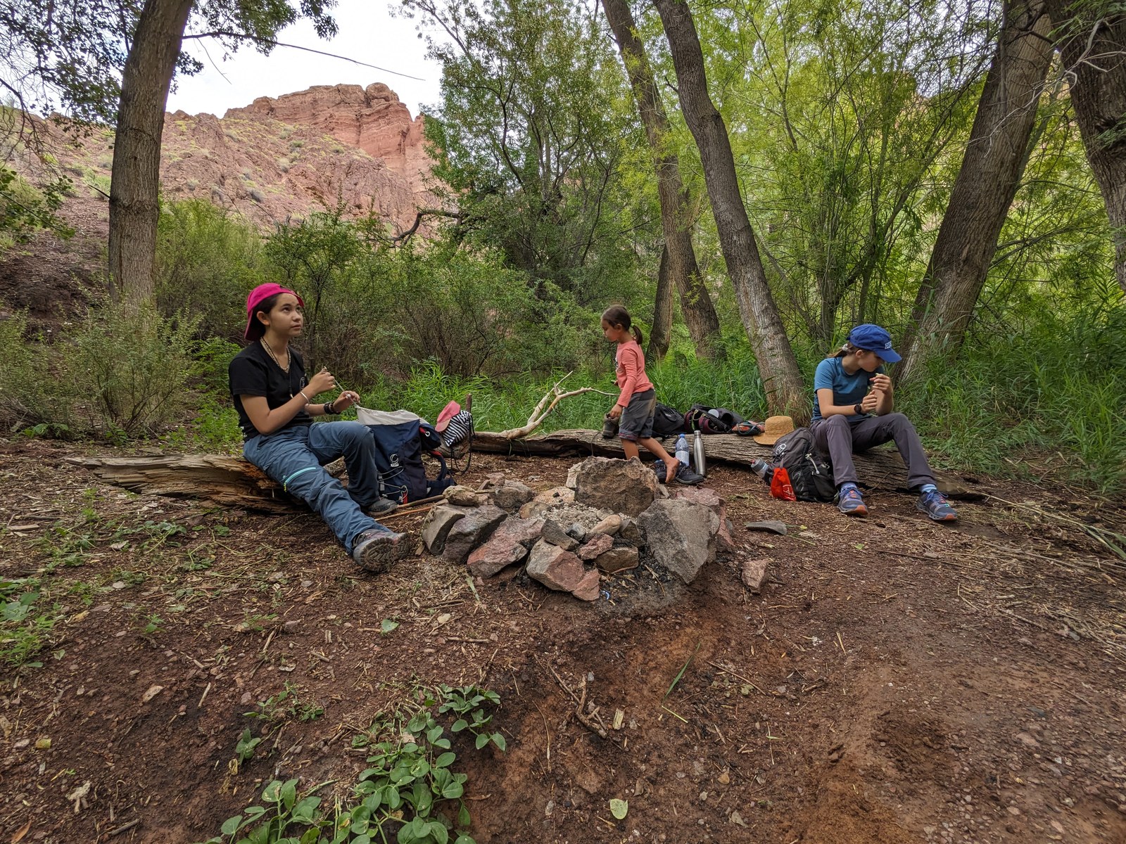 Guests resting around the campfire ring at Temirlik Canyon riverside campsite — signature overnight camping expedition from Almaty, Kazakhstan